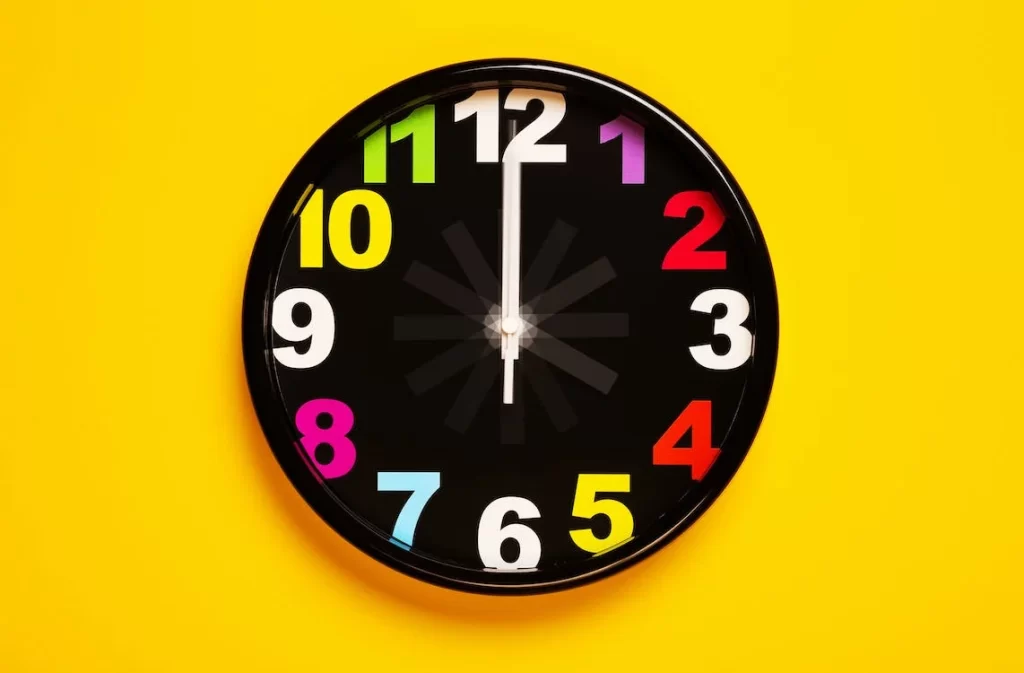 Black clock on yellow background. Find out when is the best time to send a text blast.