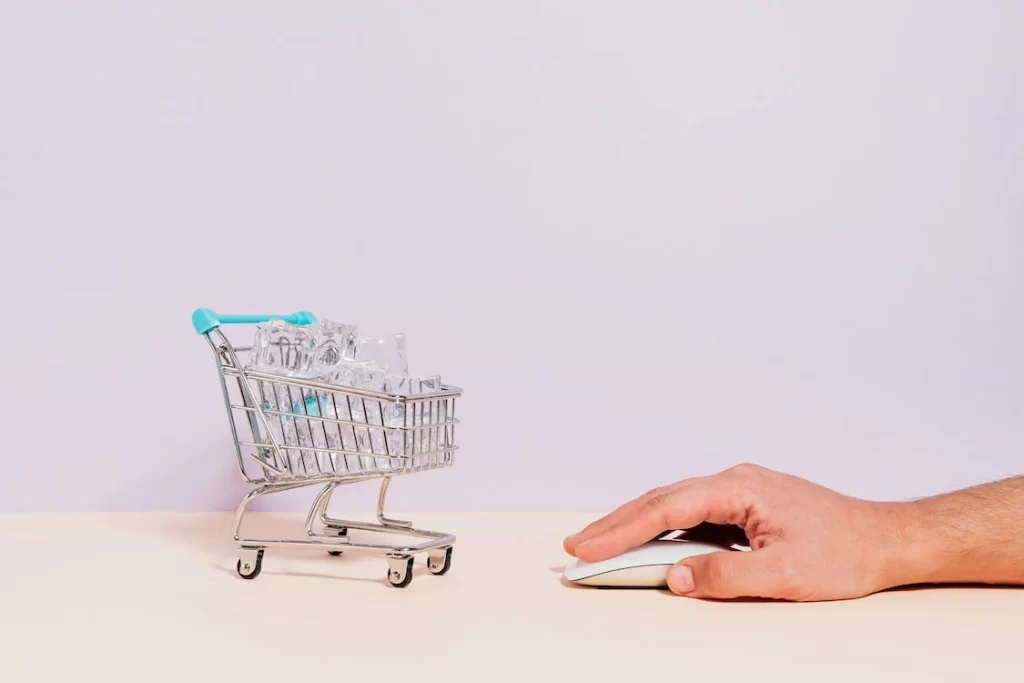 A hand clicking on a mouse with a shopping cart next to it. Analyze SMS click through rate and optimize campaigns to earn more clicks!